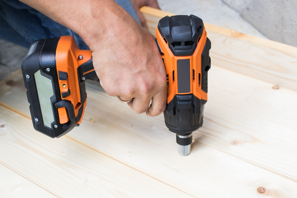 man using impact wrench on wood