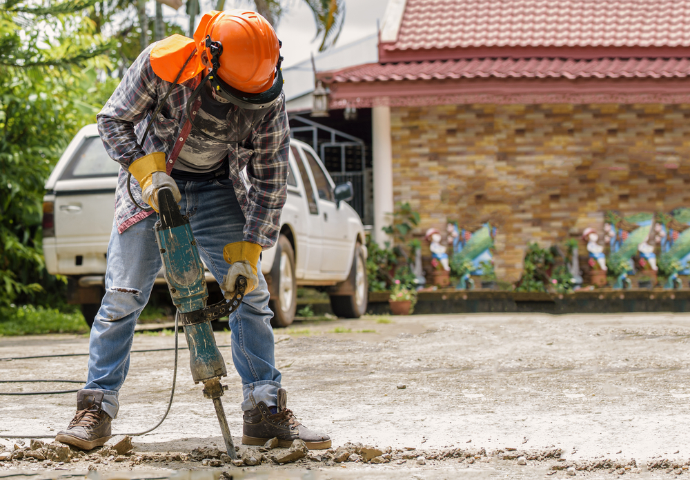 worker using demolition hammer on asphalt