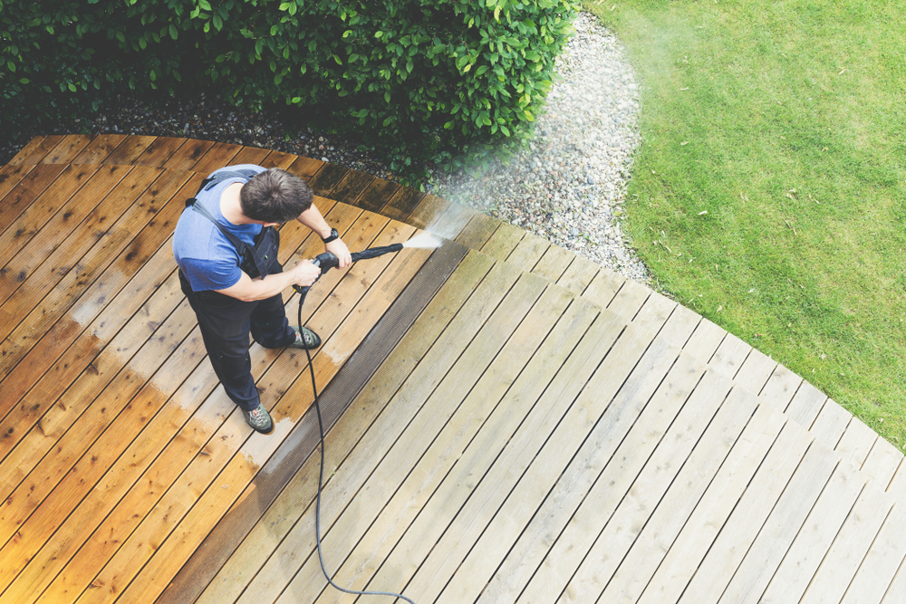 man cleaning wood decking with pressure washer