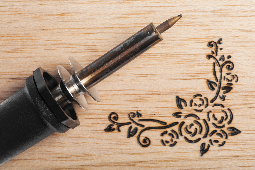 Soldering iron next to floral pyrography
