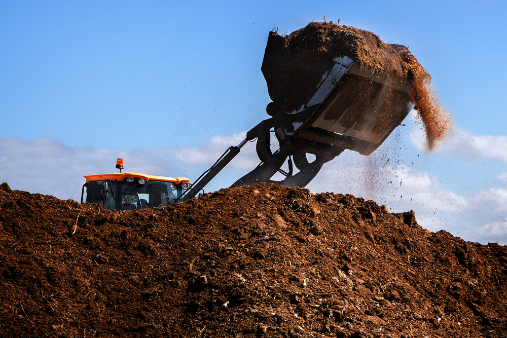 large excavator working on manure heap