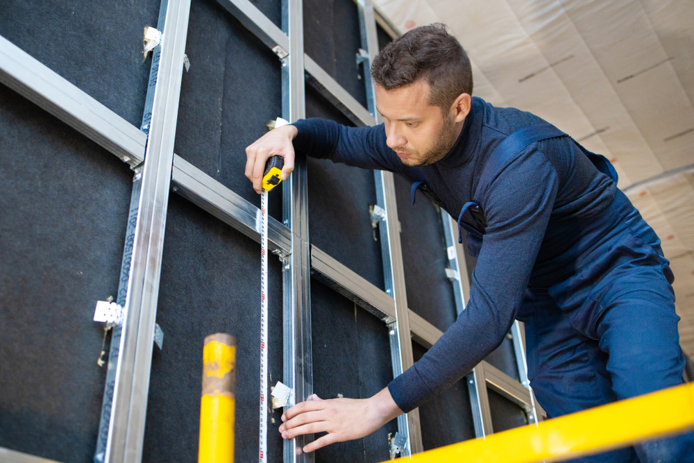 man installing metal studs for soundproofing