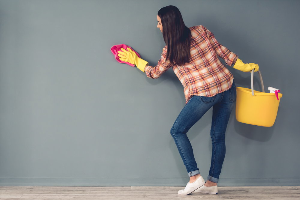 woman holding cleaning supplies while cleaning wall