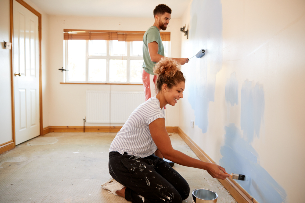 man and woman painting a beige room blue