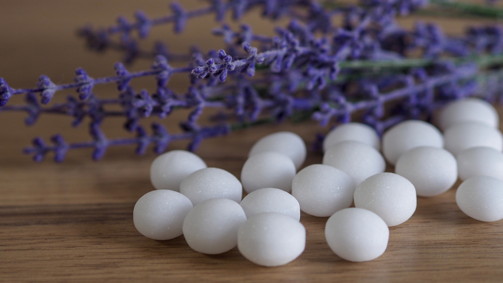 pile of white mothballs in foreground with lavender sprig in background
