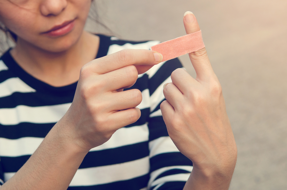 woman putting Band-Aid on cut finger
