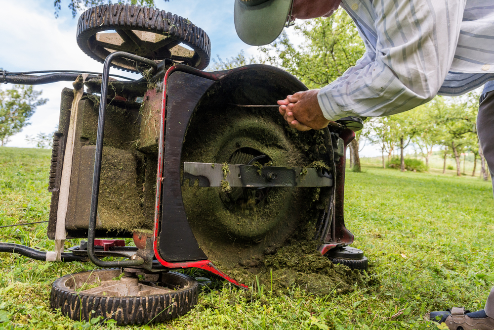 A person cleaning a lawn mower