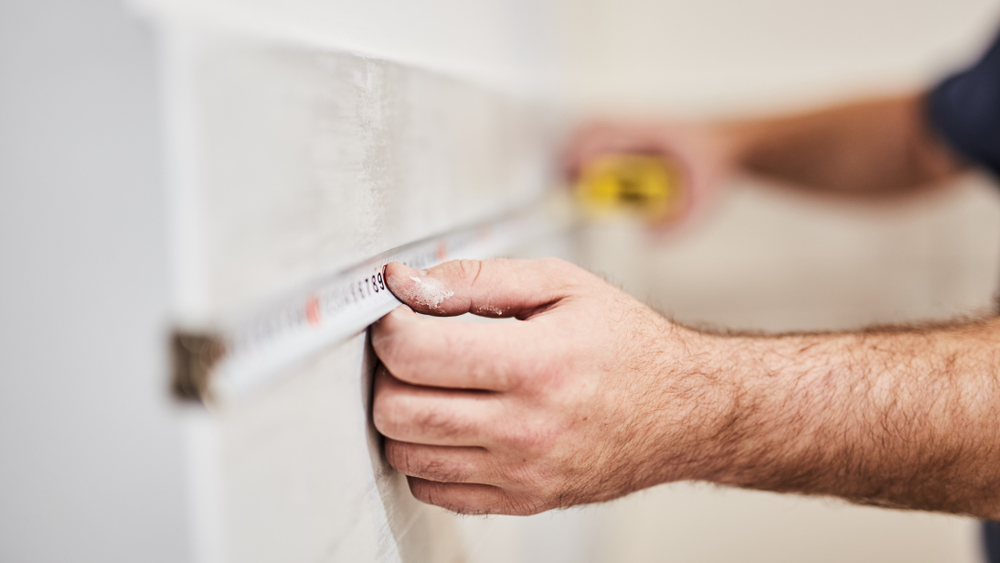 A workman measuring tiles for a renovation project