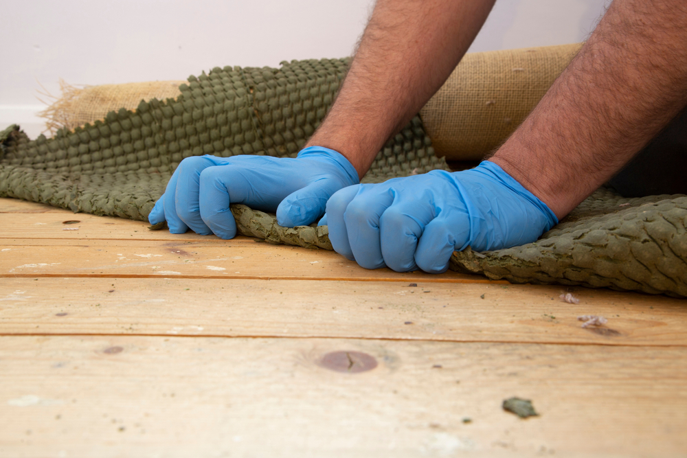 Hands Removing Carpet From Hardwood 