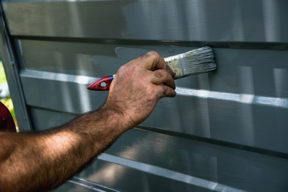 Using a paint brush to paint a garage door