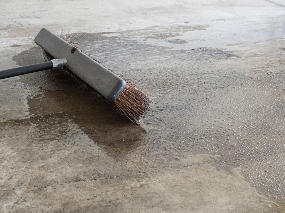a brush sweeps a concrete floor