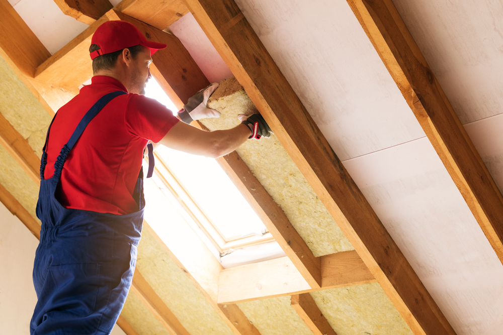 a man fits insulation onto his attic walls
