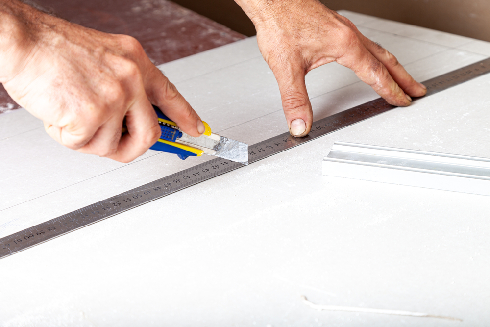 a utility knife and ruler are being used to cut a board