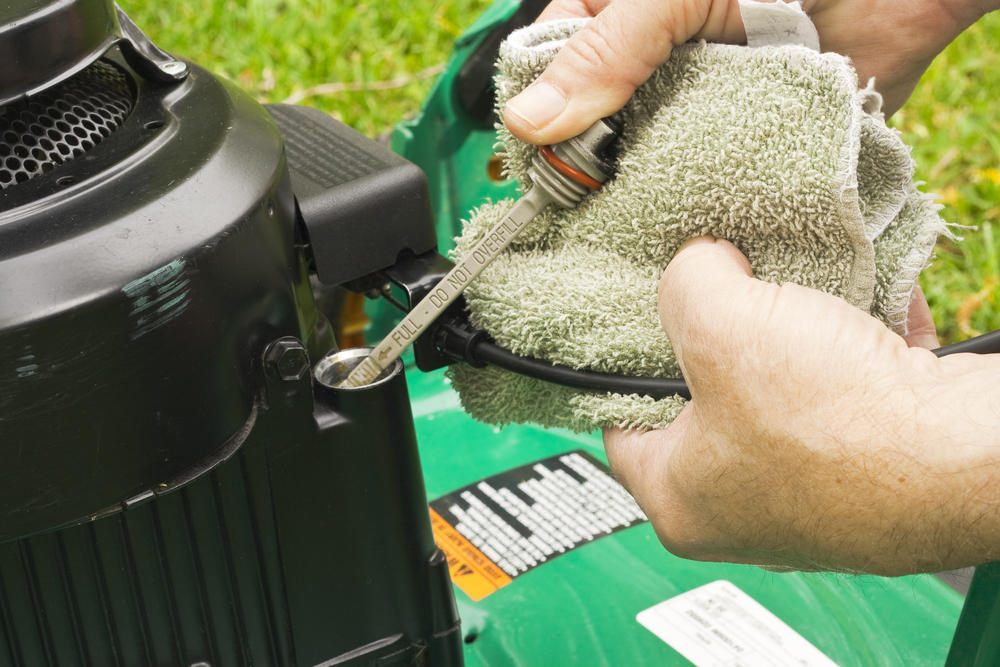 checking the dipstick on a lawn mower