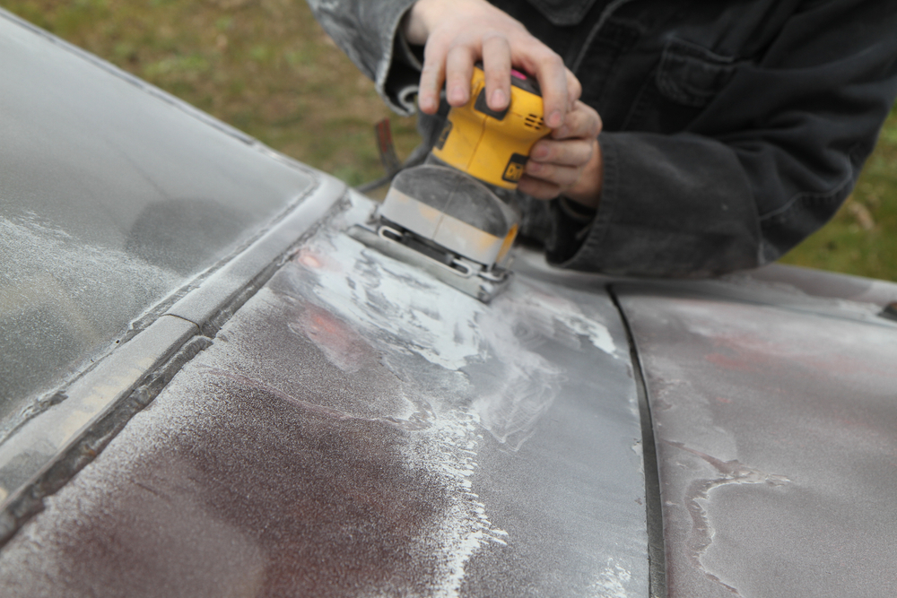 mechanic sanding chrome on car hood