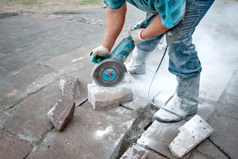 worker using circular saw to cut paver