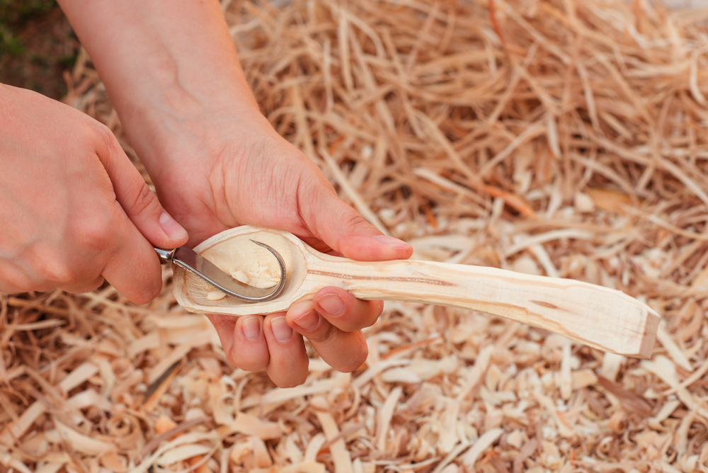 A spoon being carved with a hook knife