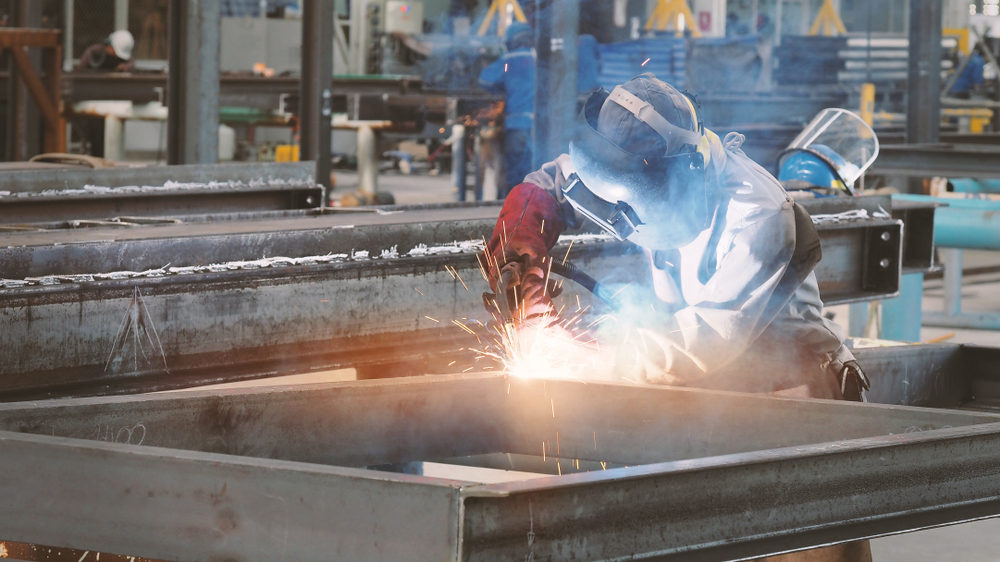 A worker using a flux core welder in a workshop