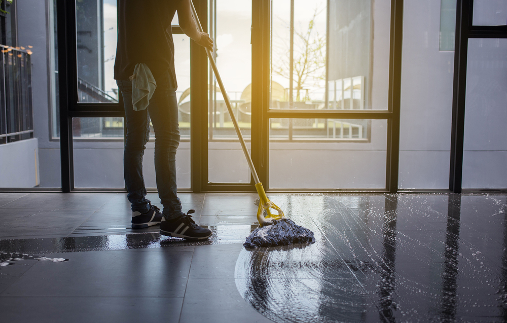 a man mops a tile floor leaving behind a wet figure-eight pattern