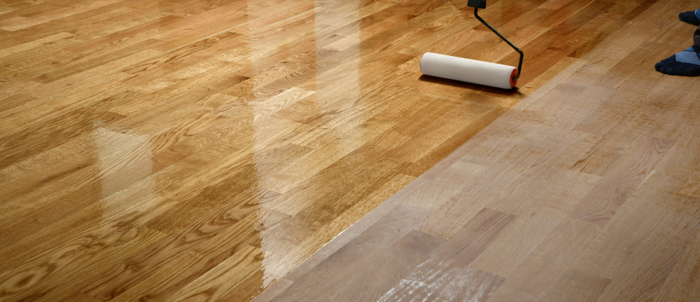 person applying lacquer to a hardwood floor