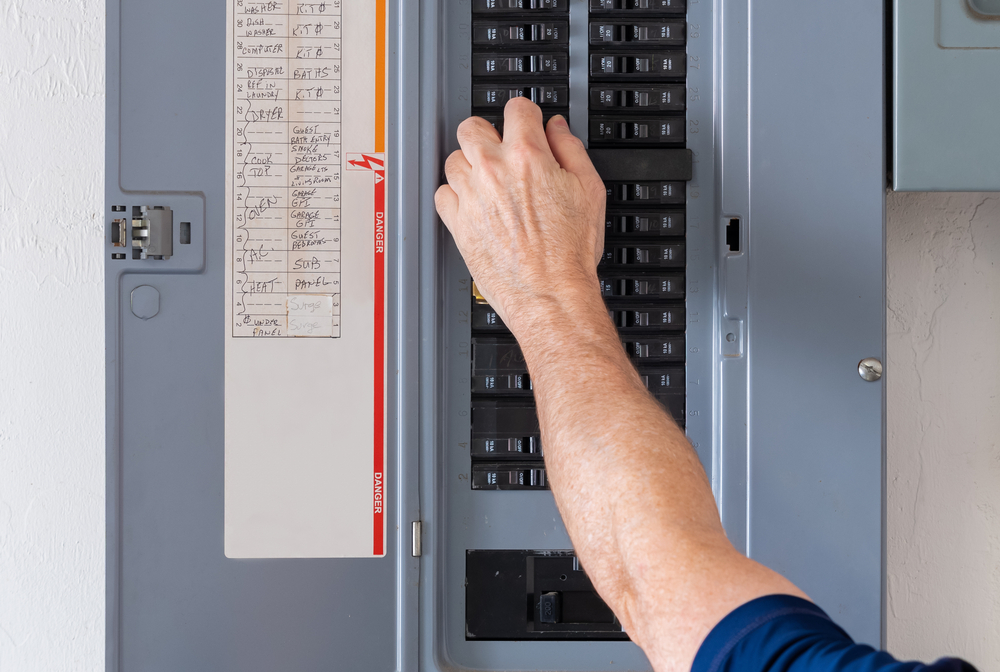 man flicking switches on breaker box at home